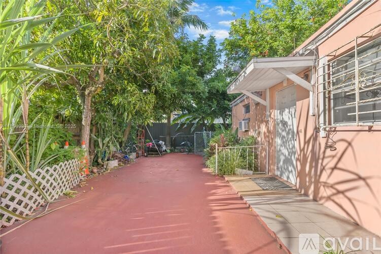 A red pathway leads through a lush garden and between two houses.