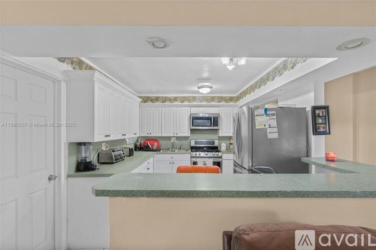 A kitchen with white cabinets and a green countertop.