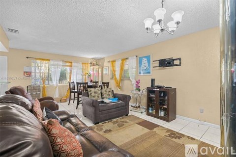 A living room with a brown leather couch and a chandelier.