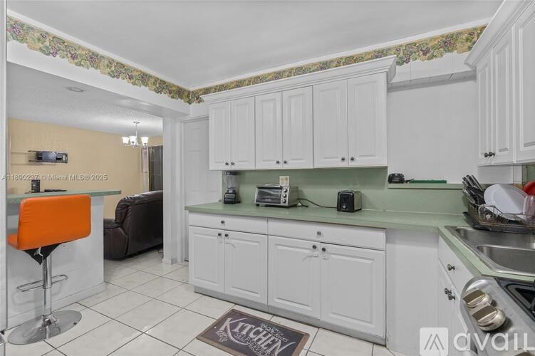 A kitchen with white cabinets and a green island.