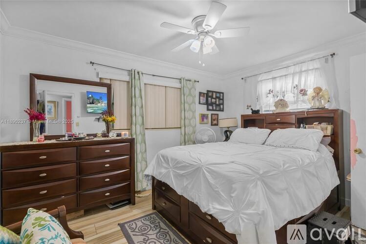 A bedroom with a white bed and a wooden dresser.