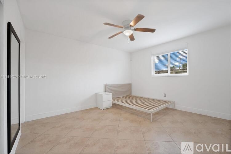 A room with a ceiling fan, a window with blinds, and a bench.