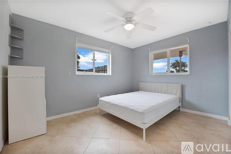 A bedroom with a bed, a ceiling fan, and two windows.