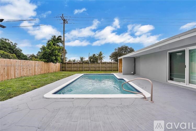 A pool in a backyard with a wooden fence and a house in the background.