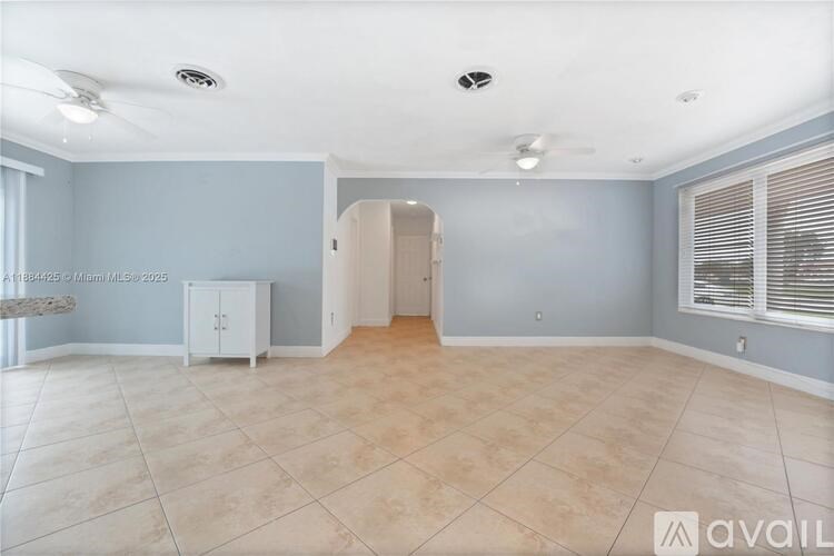 A spacious room with a cabinet and a doorway leading to another room.
