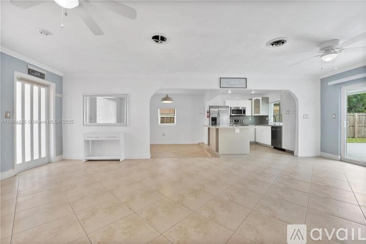 A spacious living room with a kitchen in the background.