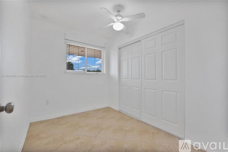 A room with a ceiling fan and a window with blinds.