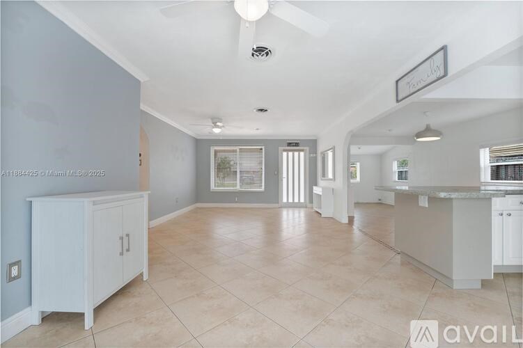 A spacious kitchen and living room with white cabinetry and tiled flooring.