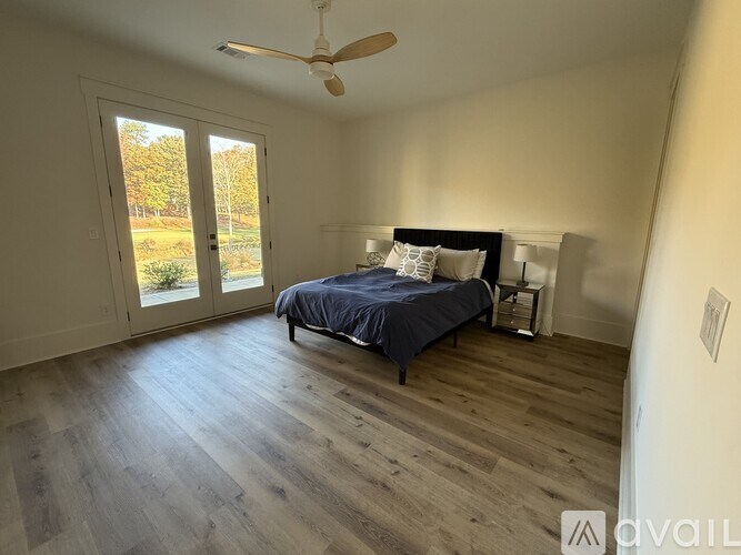 A bedroom with a bed, a ceiling fan, and a sliding glass door.
