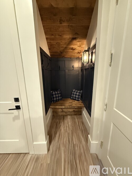 A hallway with a wooden ceiling and floor, and white walls.