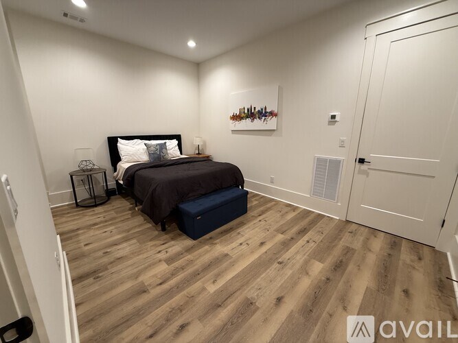 A bedroom with a bed, nightstand, and a painting on the wall.