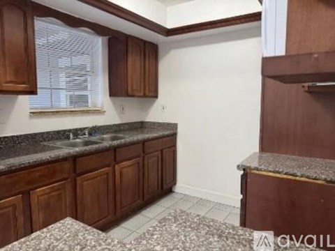 A kitchen with brown cabinets and a granite countertop.