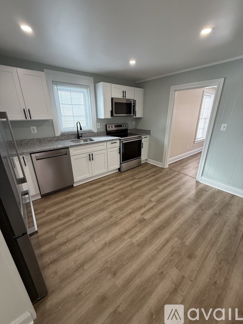 A kitchen with white cabinets and wooden flooring.