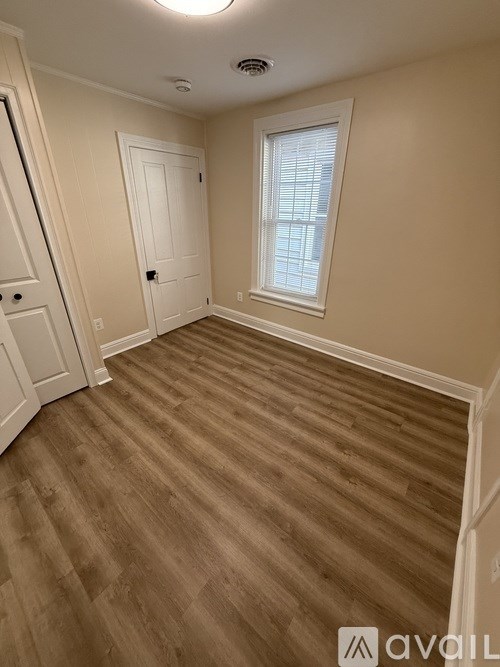 A room with a wooden floor and a window with blinds.