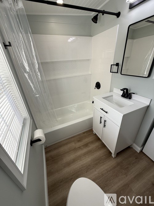 A white bathroom with a sink, mirror, and shower.