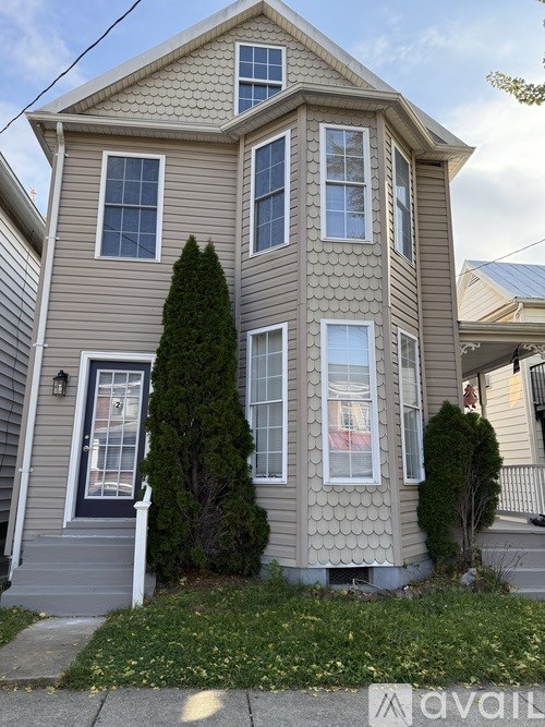 A two-story house with a front yard and a tree.