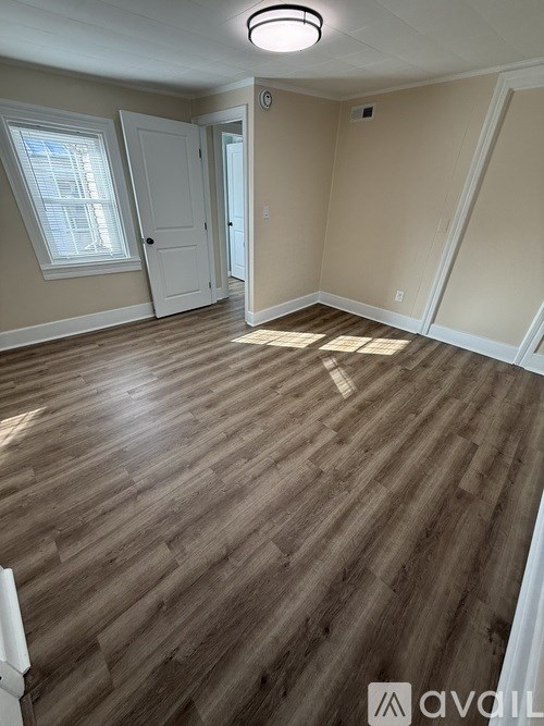 A room with wooden flooring and white walls.