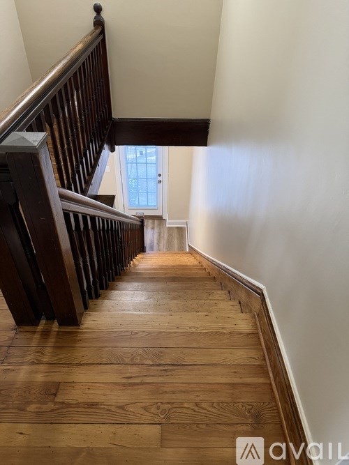 A wooden staircase with a white wall on one side and a window on the other.