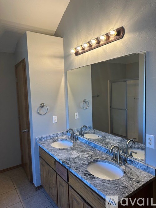 A bathroom with a granite countertop and a mirror with lights above it.