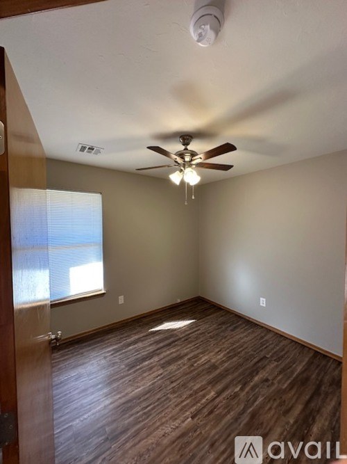 A room with a ceiling fan and wooden flooring.