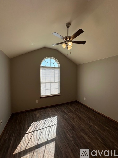 A room with a ceiling fan and a window letting in sunlight.