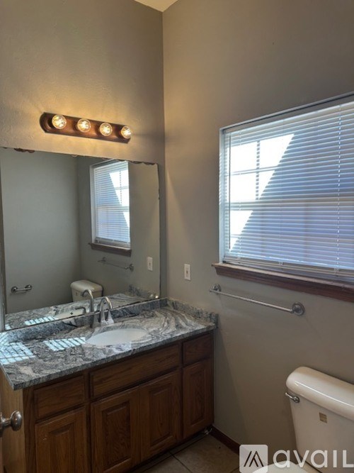A bathroom with a granite countertop and a toilet.