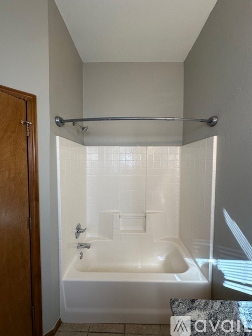 A white bathtub with a shower head and a wooden door.