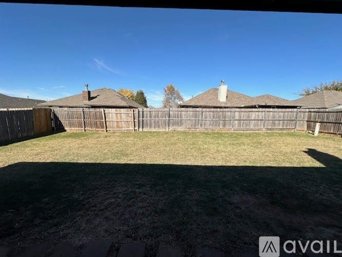 A backyard with a wooden fence and a clear blue sky.