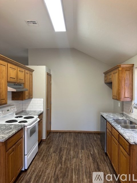 A kitchen with wooden cabinets and a white stove top oven.