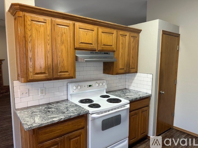 A kitchen with wooden cabinets and a white stove top oven.