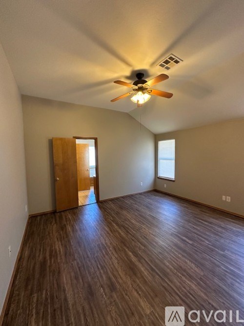 A room with a ceiling fan and wooden flooring.