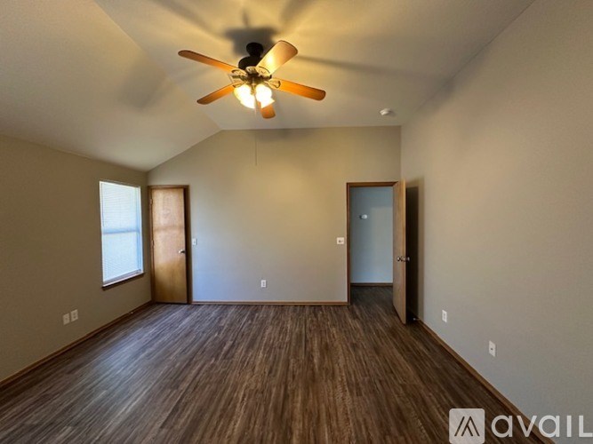A room with a ceiling fan and wooden flooring.