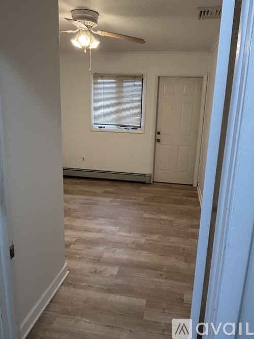 A room with a ceiling fan and a door.