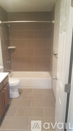 A bathroom with a toilet, tub, and tiled walls.