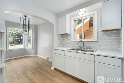 A kitchen with white cabinets and a brick backsplash.