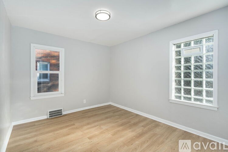 A room with a window and a wall-mounted air vent.