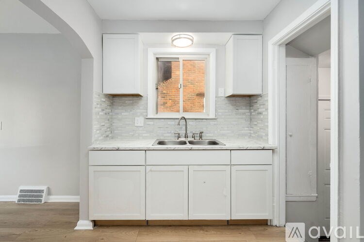A kitchen with white cabinets and a brick window.