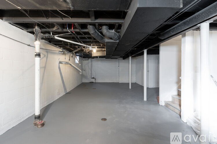A long white pipe runs along the wall of a large, empty room.