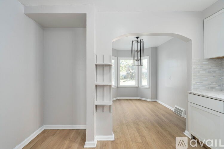A white interior space with a wooden floor and a window.