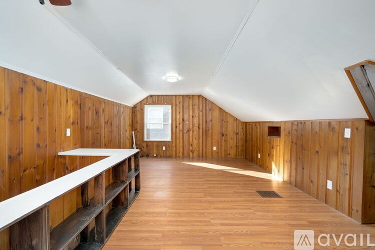 A long room with wooden walls and floor and a white bench.