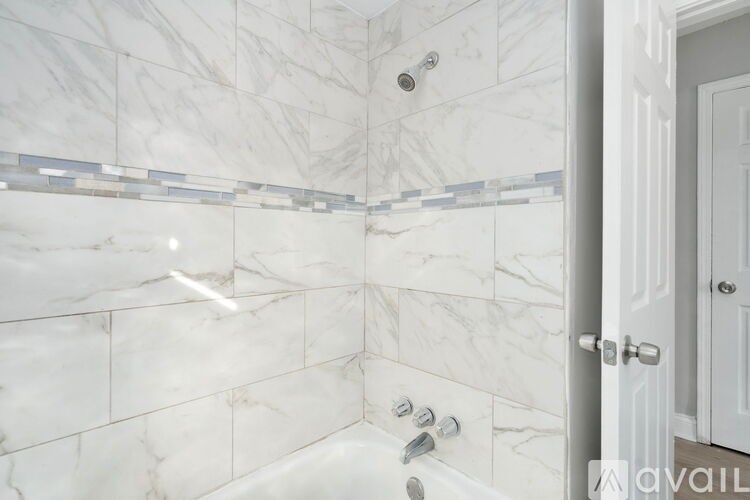 A white bathroom with a marble tile wall and a white door.