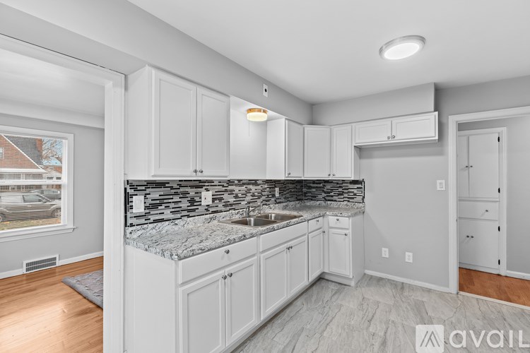 A kitchen with white cabinets and a marble countertop.
