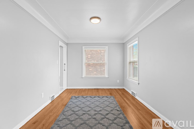 A room with a grey rug on the floor and a window with blinds.