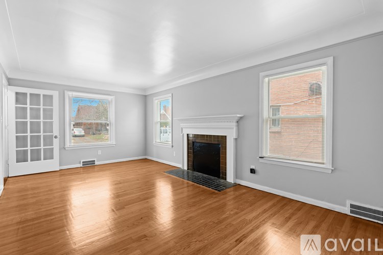 A spacious living room with a fireplace and a window overlooking a brick building.