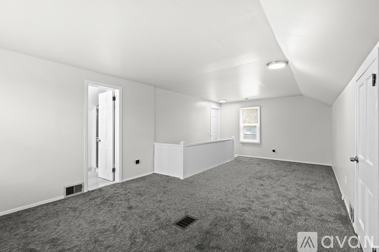 A spacious empty room with white walls and carpeted floor.