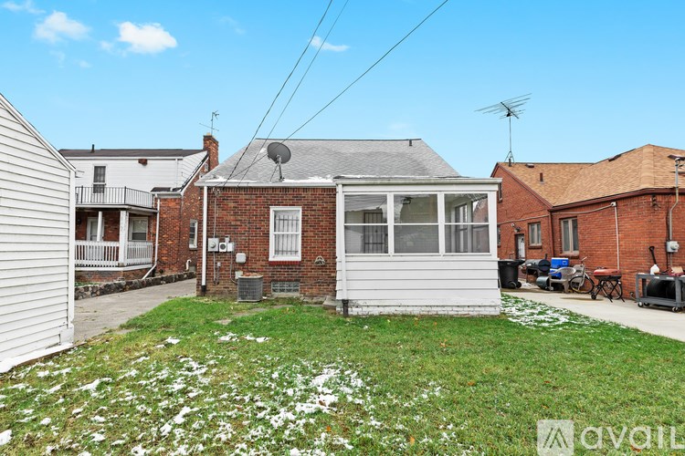 A house with a white fence and a red brick house in the background.