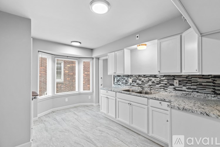 A kitchen with white cabinets and a marble countertop.