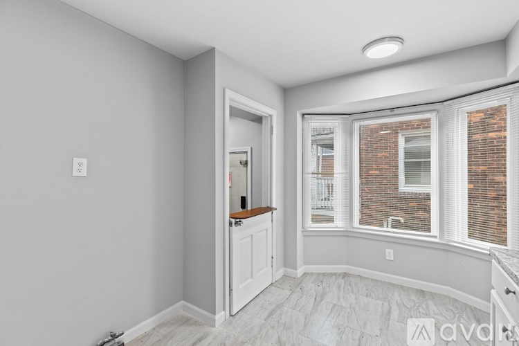A room with a white door and a window with a brick wall outside.