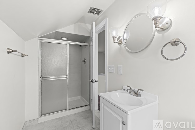 A bathroom with a white sink and a glass shower door.