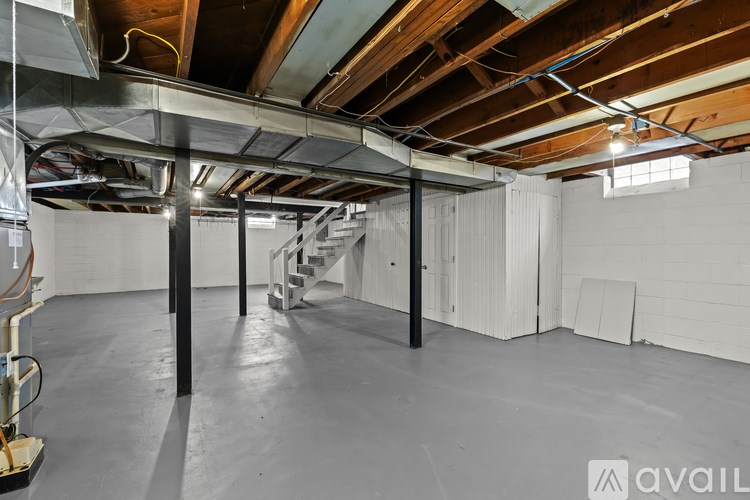 A large empty room with a concrete floor and exposed wooden beams on the ceiling.